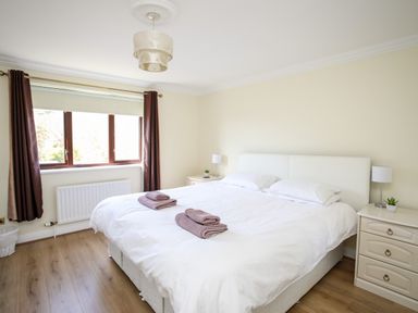 A bedroom with a large bed between two nightstands with lamps and folded towels on the bed at The Gables in Trearddur Bay