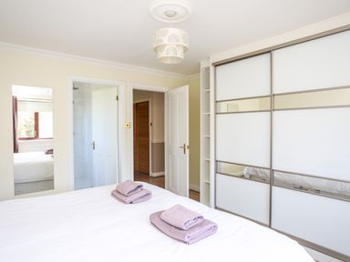 A bedroom with a bed with folded towels two doors and a wardrobe with sliding doors at The Gables in Trearddur Bay