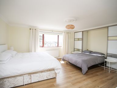 A bedroom with two beds a window with curtains and built in wardrobes at The Gables in Trearddur Bay