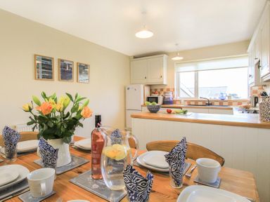 A kitchen and dining area with a set table and flowers on the table at Garnedd Lwyd in Llanfair