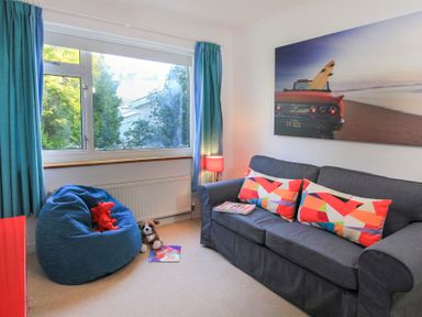 A sitting room with a blue sofa colorful cushions a bean bag and a large window at Garnedd Lwyd in Llanfair