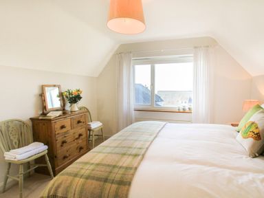 A bedroom with a bed a window two chairs and a wooden dresser at Garnedd Lwyd in Llanfair