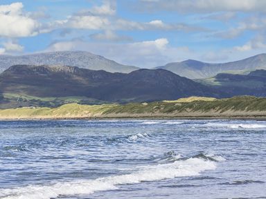 A coastal scene with waves in the foreground and mountains in the background at Garnedd Lwyd in Llanfair