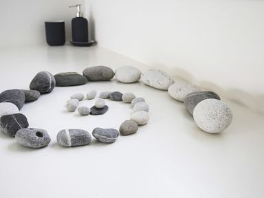 A spiral arrangement of gray and white stones on a white surface with soap dispensers in the background at Glan Dwr Bach in Glyn Garth