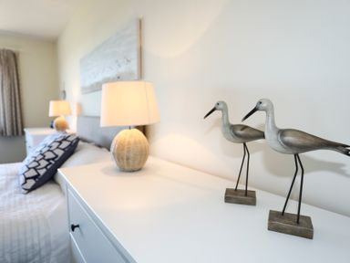 A bedroom with two table lamps wooden bird figurines and patterned pillows at Glanrhyd Uchaf in Llanfair yn Neubwll