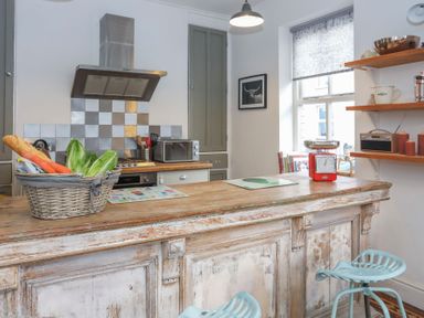 A kitchen with wooden countertops a basket of vegetables a red scale and blue stools at Gwalia Stores in Beaumaris
