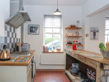 A kitchen with wooden countertops open shelves and a window with a blind at Gwalia Stores in Beaumaris