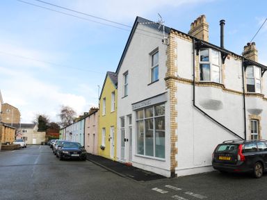A street with parked cars and a row of houses including Gwalia Stores in Beaumaris