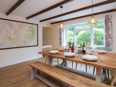 A dining room with a wooden table set for six people and a large map on the wall at Gwyndy Bach in Beddgelert