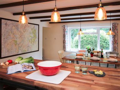 A kitchen and dining area with wooden countertops a red bowl fresh vegetables and a map on the wall at Gwyndy Bach in Beddgelert