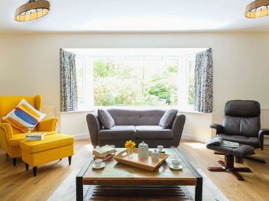 A living room with a yellow armchair gray sofa and black recliner at Gwyndy Bach in Beddgelert