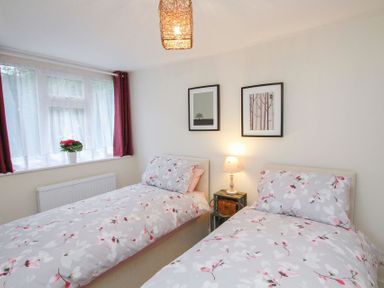 A bedroom with two single beds with floral bedding a nightstand with a lamp between the beds and two framed pictures on the wall at Gwyndy Bach in Beddgelert