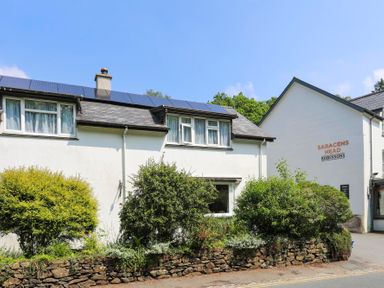 A white building with solar panels on the roof and shrubs in front at Saracens Head in Beddgelert