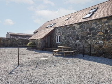 A stone building with skylights and a wooden picnic table on a gravel area at Hafod in Pontllyfni