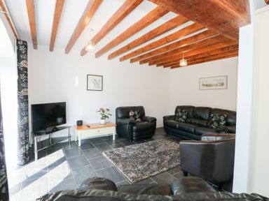 A living room with leather sofas a television and wooden ceiling beams at Hafod in Pontllyfni