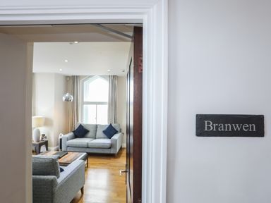 A living room with two grey sofas a wooden coffee table a floor lamp and a window at Harlech Apartments - Branwen in Harlech