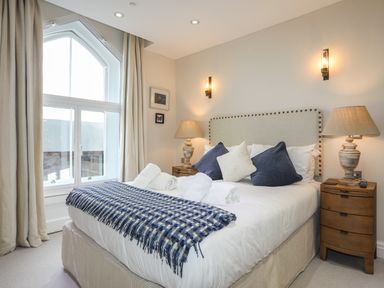 A bedroom with a bed with pillows and rolled towels beside a window at Harlech Apartments - Branwen in Harlech