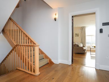 A wooden staircase with carpeted steps next to an open door leading to a living room at Harlech Apartments - Bendigeidfran in Harlech