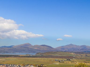 A landscape view of fields with houses in the foreground and mountains in the background at Harlech Apartments - Bendigeidfran in Harlech