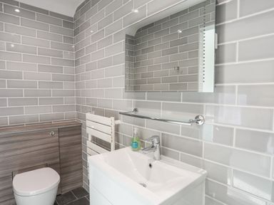 A bathroom with a toilet wooden panel sink with faucet mirror and towel rack at Harlech Apartments - Matholwch in Harlech