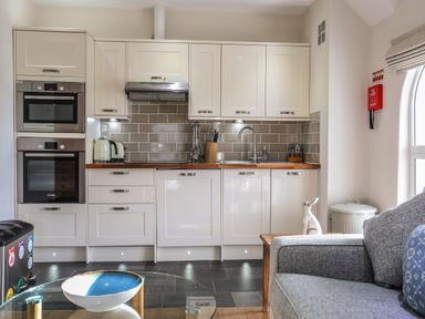 A kitchen with white cabinets wooden countertop and tiled backsplash at Harlech Apartments - Matholwch in Harlech