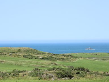 A coastal landscape with grassy hills overlooking the sea at Hen Gilfach in Llanfairyngnhornwy