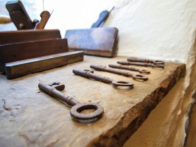 A row of old metal keys on a stone surface with wooden tools in the background at Hen Gilfach in Llanfairyngnhornwy