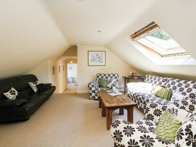 A living room with floral pattern sofas a black sofa wooden table a skylight window and a side table with flowers at Hen Gilfach in Llanfairyngnhornwy