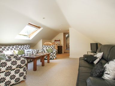 A living room with patterned sofas wooden coffee table and television at Hen Gilfach in Llanfairyngnhornwy