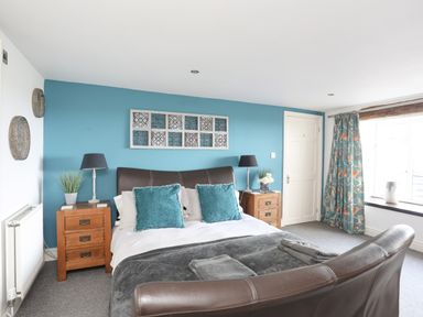 A bedroom with a double bed with teal cushions and wooden bedside tables at Hen Gilfach in Llanfairyngnhornwy