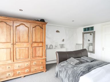 A bedroom with a wooden wardrobe gray bed and towels on the bed at Hen Gilfach in Llanfairyngnhornwy