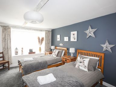 A bedroom with two single beds wooden side tables lamps and wall decor at Hen Gilfach in Llanfairyngnhornwy