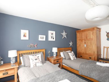 A bedroom with two single wooden beds bedside tables lamps and a wooden wardrobe at Hen Gilfach in Llanfairyngnhornwy