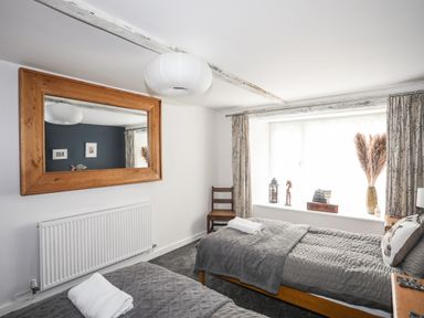 A bedroom with two single beds and a large wooden framed mirror at Hen Gilfach in Llanfairyngnhornwy