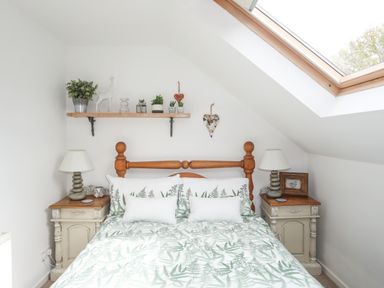 A bedroom with a wooden bed and bedside tables under a skylight window at Hen Gilfach in Llanfairyngnhornwy