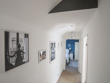 A hallway with framed pictures on the wall and a view into a bedroom with a blue wall at Hen Gilfach in Llanfairyngnhornwy
