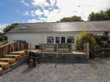 An outdoor patio area with wooden benches flower pots and a grill at Hen Gilfach in Llanfairyngnhornwy