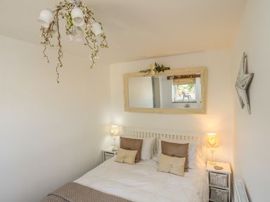 A bedroom with a double bed with pillows two bedside tables with lamps a mirror above the bed and a star decoration on the wall at Hen Gilfach Stable in Llanfairyngnhornwy