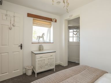 A bedroom corner with a small cabinet under a window and a door leading outside at Hen Gilfach Stable in Llanfairyngnhornwy
