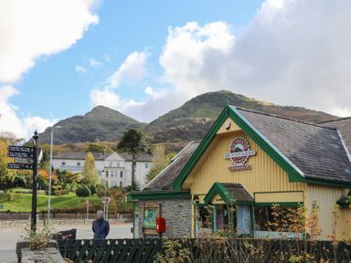A railway station building with snowdon mountain railway sign and mountains in the background at Hirfron in Llanberis