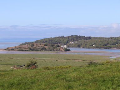 A landscape with grassy fields water and trees at Big House in Llandecwyn