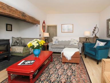 A living room with a red coffee table and blue vase with flowers at Big House in Llandecwyn