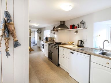 A kitchen with a stove microwave washing machine dishwasher and sink at Big House in Llandecwyn
