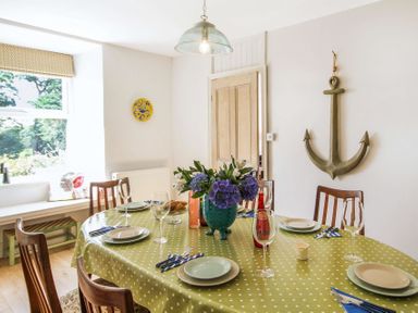 A dining room with a polka dot tablecloth a flower vase and an anchor wall decoration at Big House in Llandecwyn