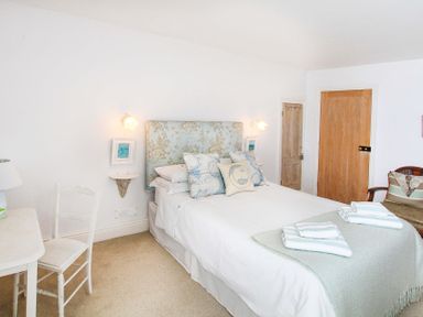 A bedroom with a bed with pillows and folded towels a chair a desk and two doors at Big House in Llandecwyn