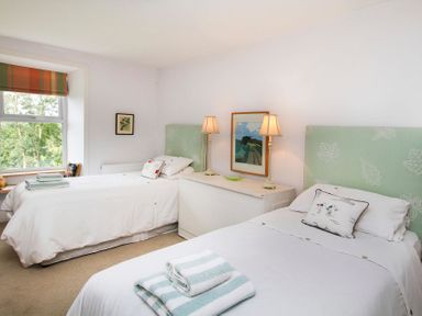 A bedroom with two single beds lamps and a window at Big House in Llandecwyn