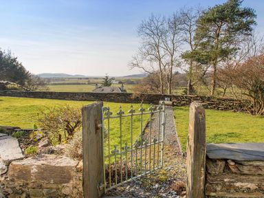A garden gate opening to a gravel path with grass and stone walls at Big House in Llandecwyn