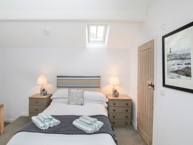 A bedroom with a double bed bedside tables lamps and a framed picture on the wall at Big House in Llandecwyn