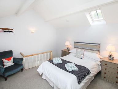 A bedroom with a bed chairs lamps and skylight at Big House in Llandecwyn