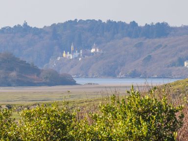 A landscape view of a body of water with hills and buildings in the background at Big House in Llandecwyn